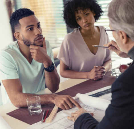 Man at desk discussing plans with young couple