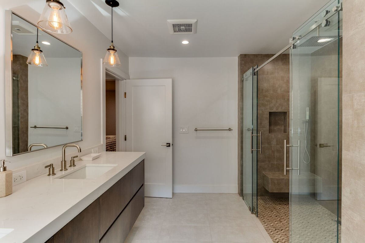 A bathroom with a double sliding glass door walk-in shower and large vanity, part of a custom home build in Sherman Oaks, CA by A-List Builders.