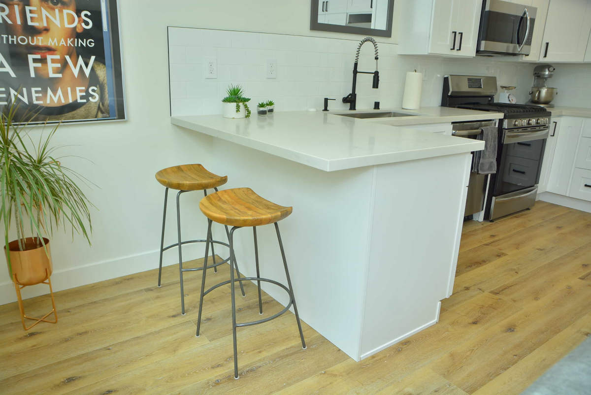 Bar seating at a new, polished stone kitchen counter, part of a home remodel in Beverlywood, CA by upscale Los Angeles design-build firm A-List Builders.