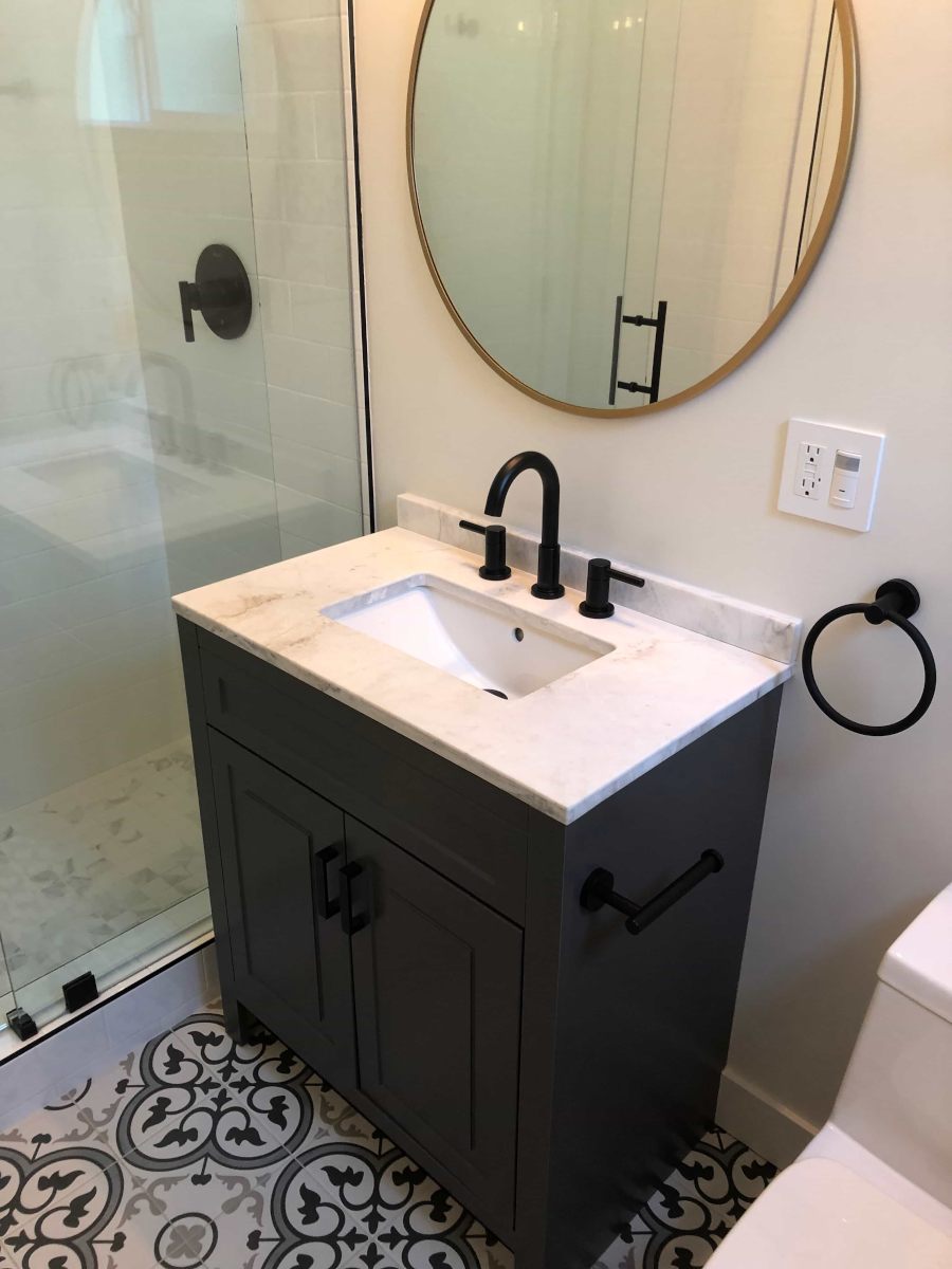 A simple bathroom vanity with wood cabinets, marble top, and brushed bronze faucet, part of a complete home remodel in Beverlywood, CA by A-List Builders.