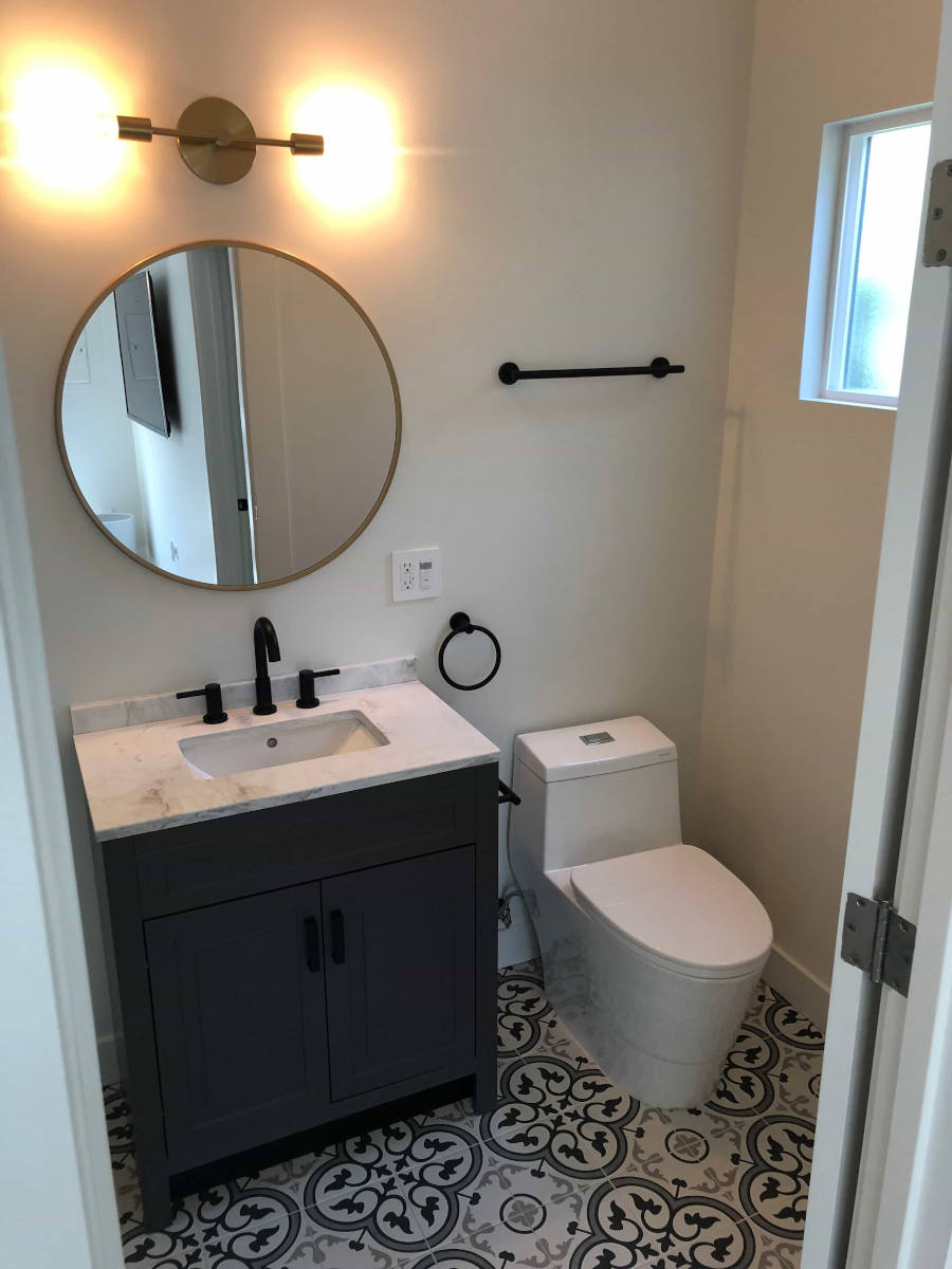 A newly remodeled bathroom with cheery floor patterns and a posh new vanity and mirror, part of a complete home remodel in Beverlywood, CA by A-List Builders.