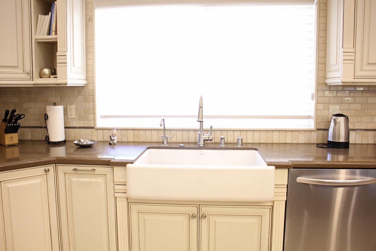 A newly remodeled kitchen sink, window, and counters, all in cream, part of a Sherman Oaks, CA home remodel by Los Angeles design-build firm A-List Builders.