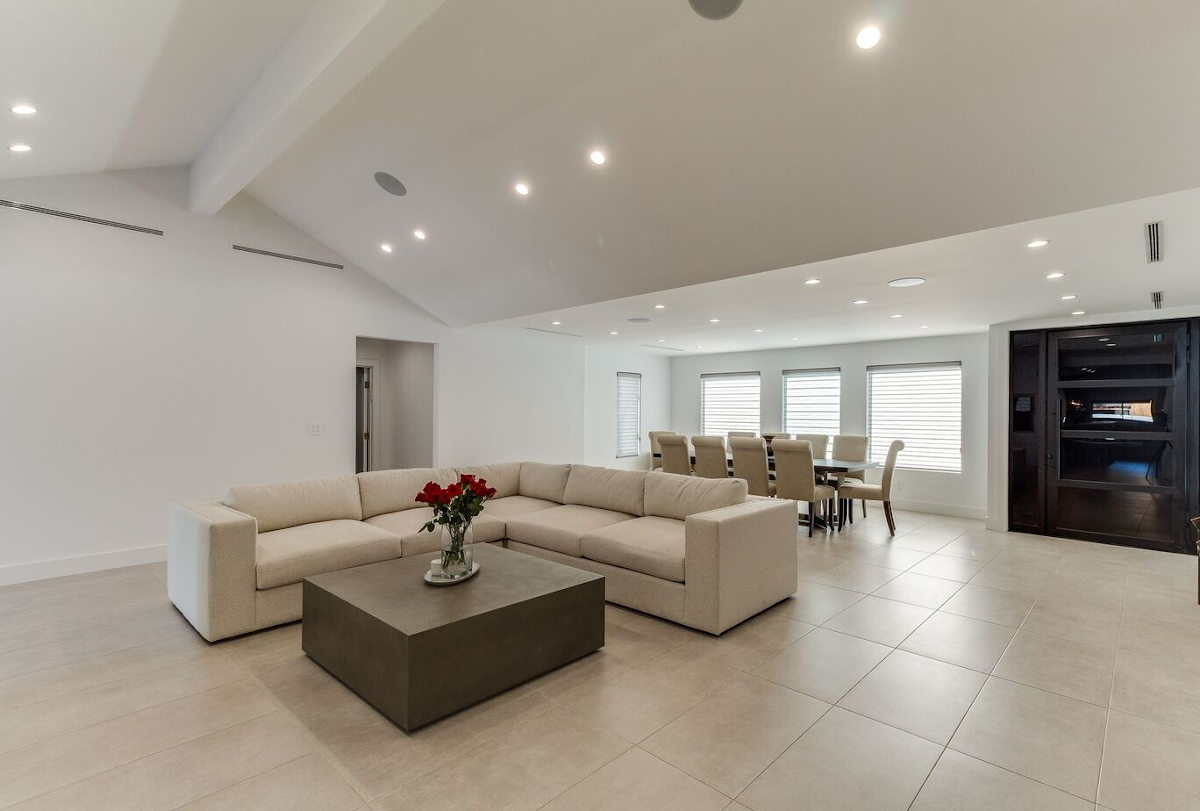 A minimalist, all-white family room and dining area in a home in Sherman Oaks, CA, part of a home remodel by Los Angeles design-build firm A-List Builders.