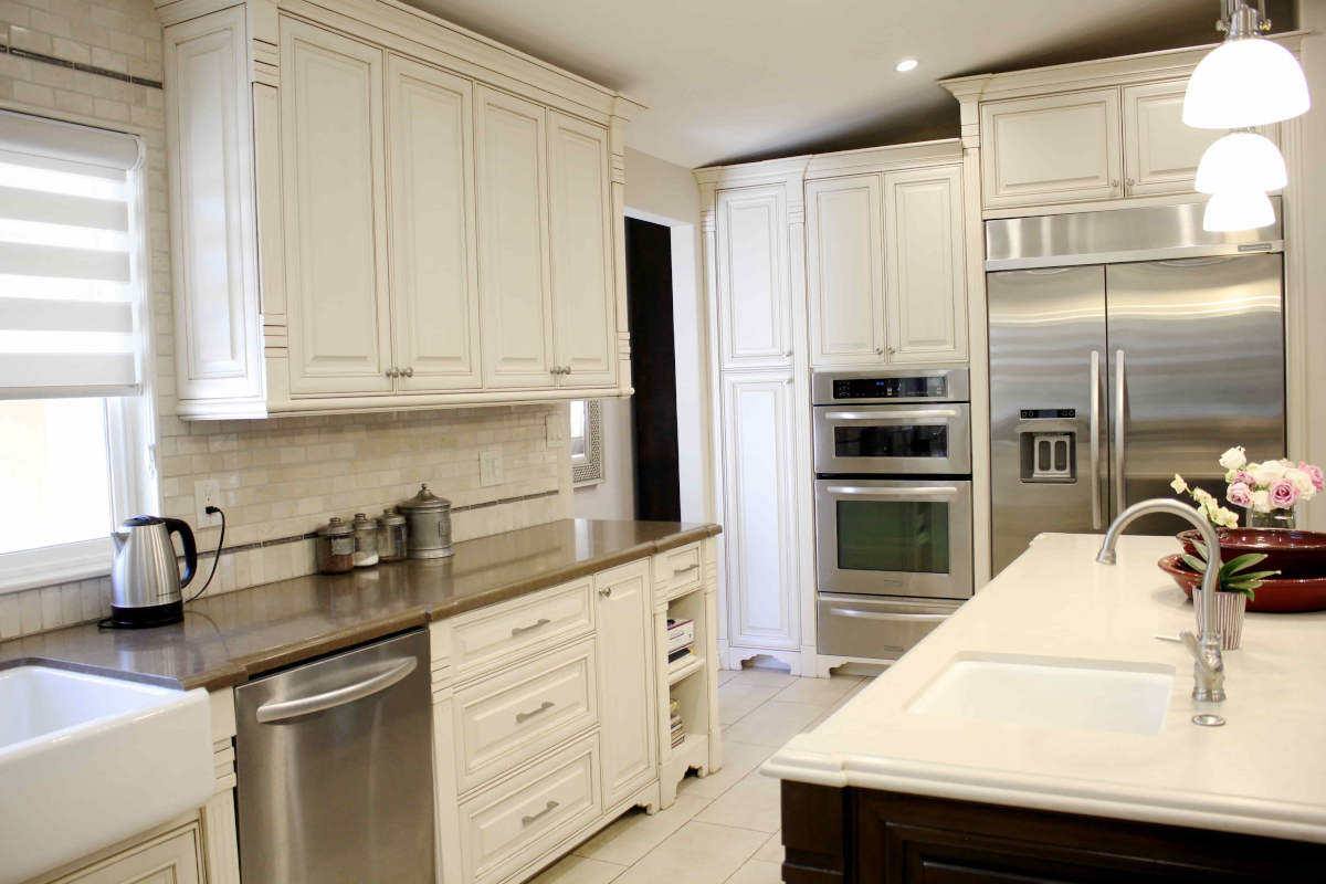 A newly remodeled Sherman Oaks, CA home kitchen, with white cabinetry and tiling, and stainless steel appliances, by LA design-build firm A-List Builders.