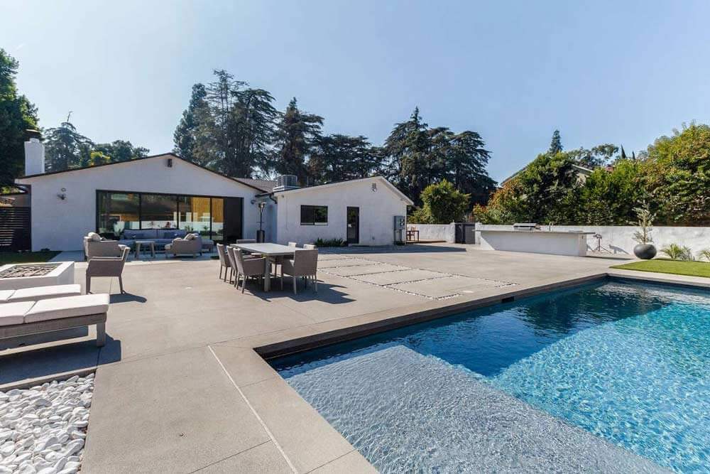 A large hardscaped backyard area, with swimming pool in the fore, part of a Sherman Oaks, CA home remodel by Los Angeles design-build firm A-List Builders.