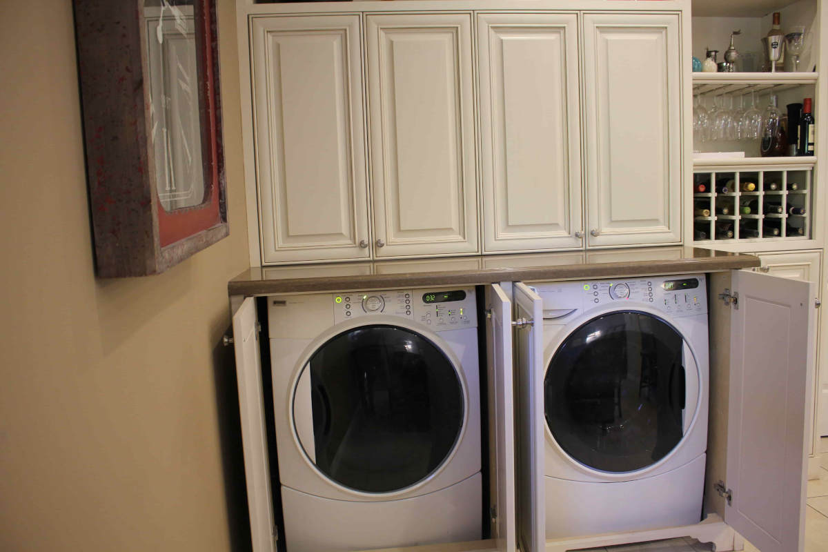 A washer and dryer are hidden behind white cabinets, part of a home remodel in Sherman Oaks, CA by Los Angeles design-build firm A-List Builders.