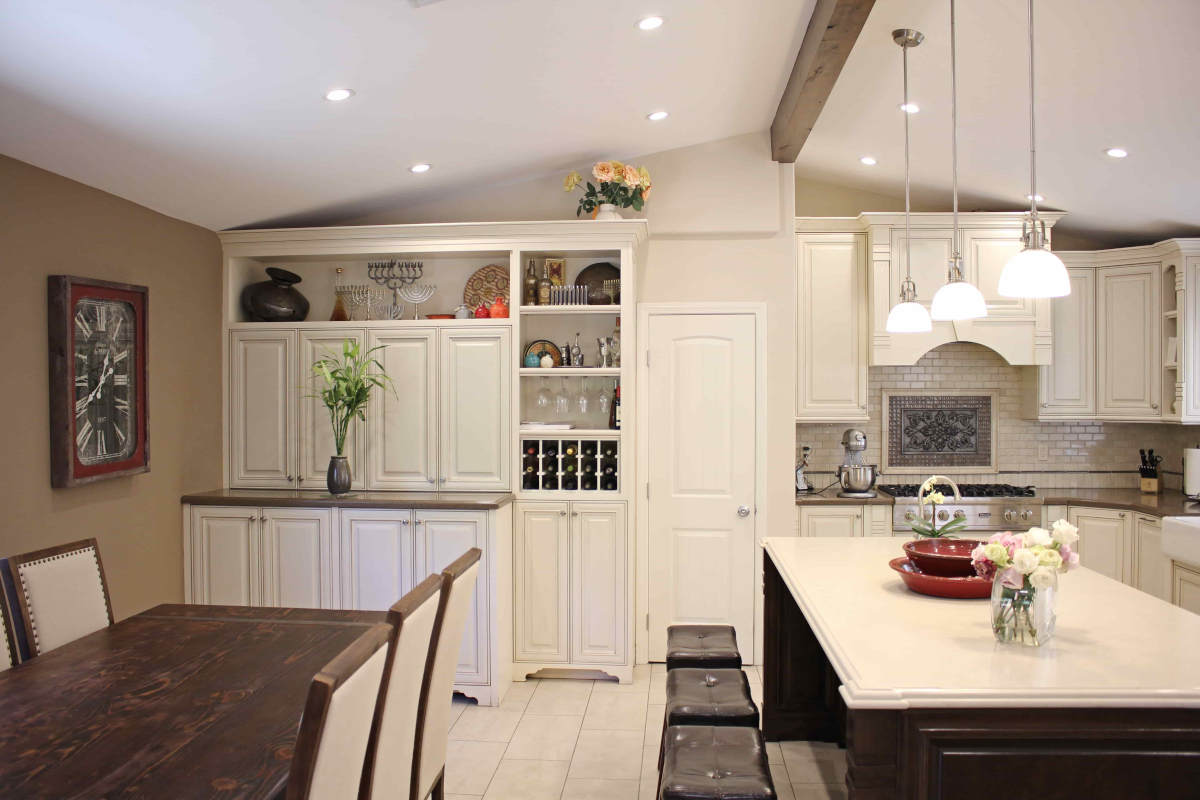 White cabinets, a kitchen island, and formal dining area at a home in Sherman Oaks, CA, part of a home remodel by Los Angeles design-build firm A-List Builders.