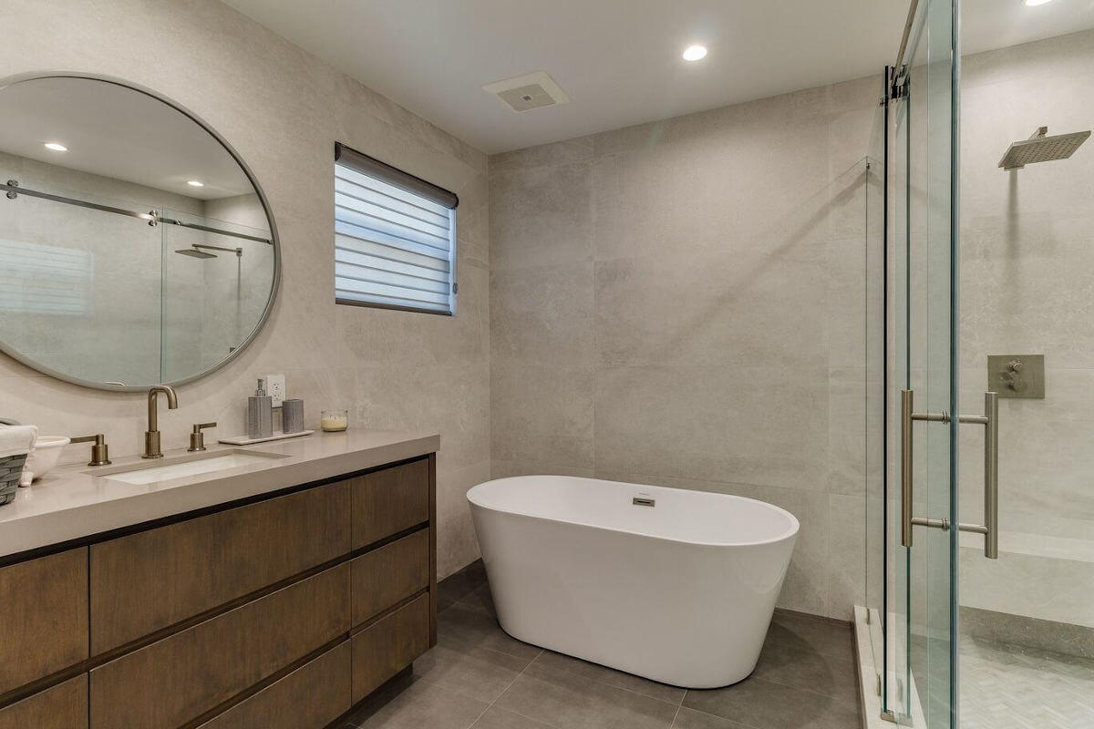 A freestanding no-leg tub and luxurious bathroom vanity with wood cabinetry, part of a home remodel in Sherman Oaks, CA by LA design-build firm A-List Builders.