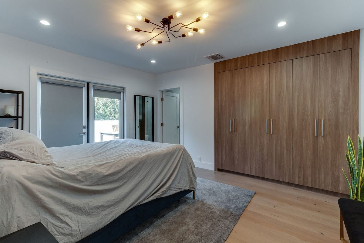 A newly remodeled bedroom with a large wooden closet and swanky ceiling lights, part of a home remodel in Sherman Oaks, CA by design-build firm A-List Builders.