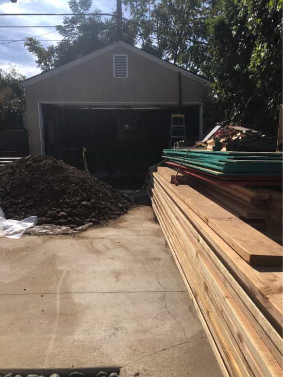 Lumber and a pile of earth sit in a driveway at a house in Beverlywood, CA, part of a home remodel by Los Angeles design-build firm A-List Builders.