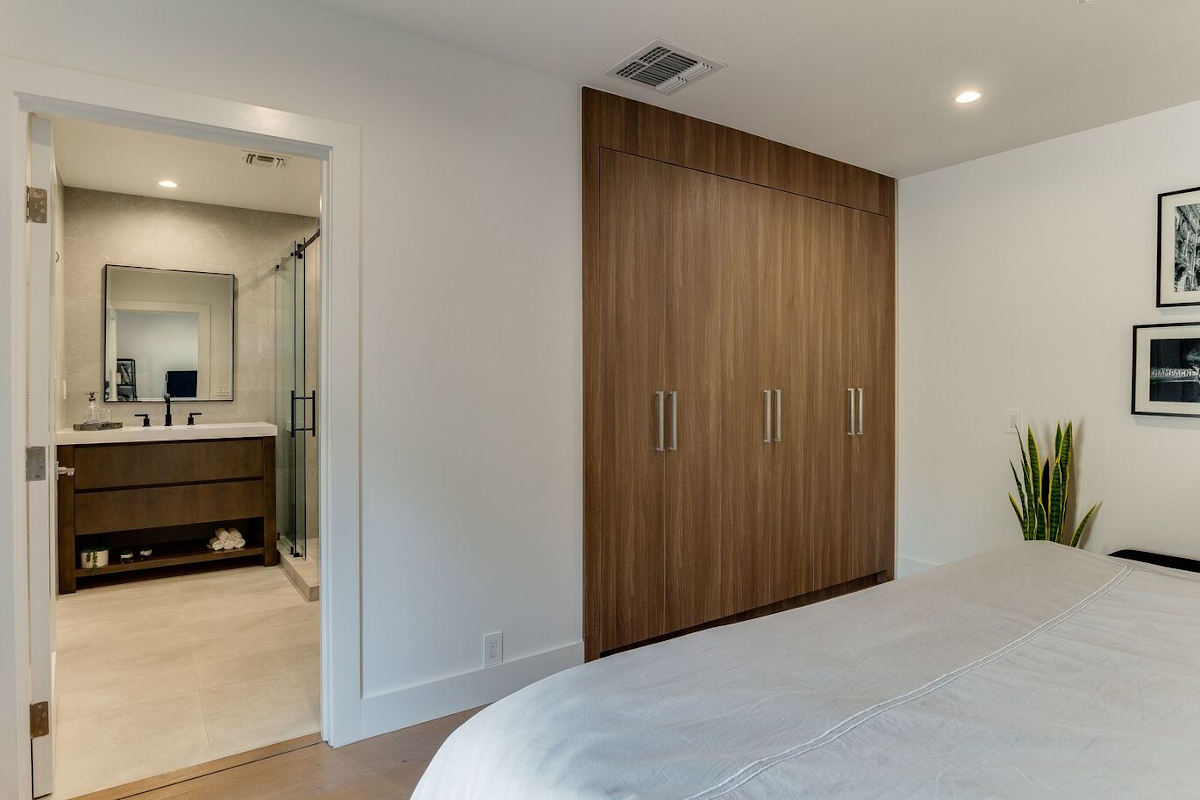 A light and airy ensuite bed and bath at a home in Sherman Oaks, CA, part of a home remodel by Los Angeles design-build firm A-List Builders.