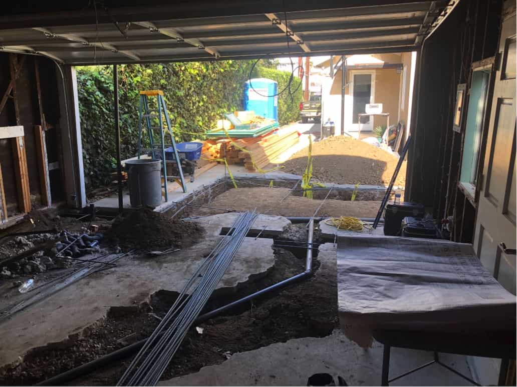 A garage and driveway are torn up to expose buried pipes, part of a home remodel in Beverlywood, CA by Los Angeles design-build firm A-List Builders.