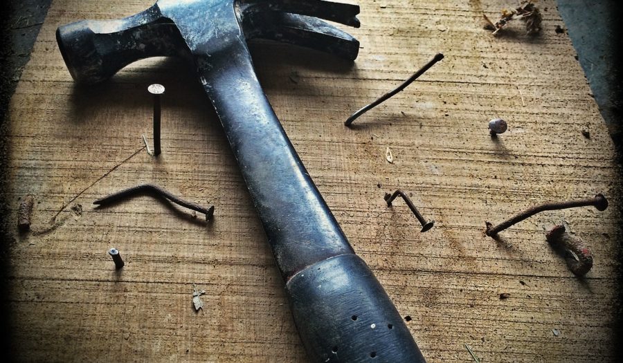 Hammer and misshapen nails on wood