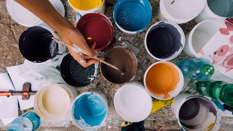 Collection of open paint cans and brushes.