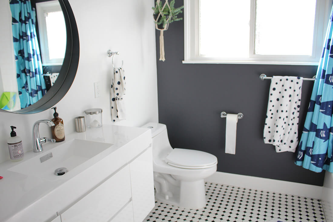 A bathroom with a dalmatian theme in the floor tiling, linens, and round black-bordered vanity mirror, part of an Encino, CA home remodel by A-List Builders.