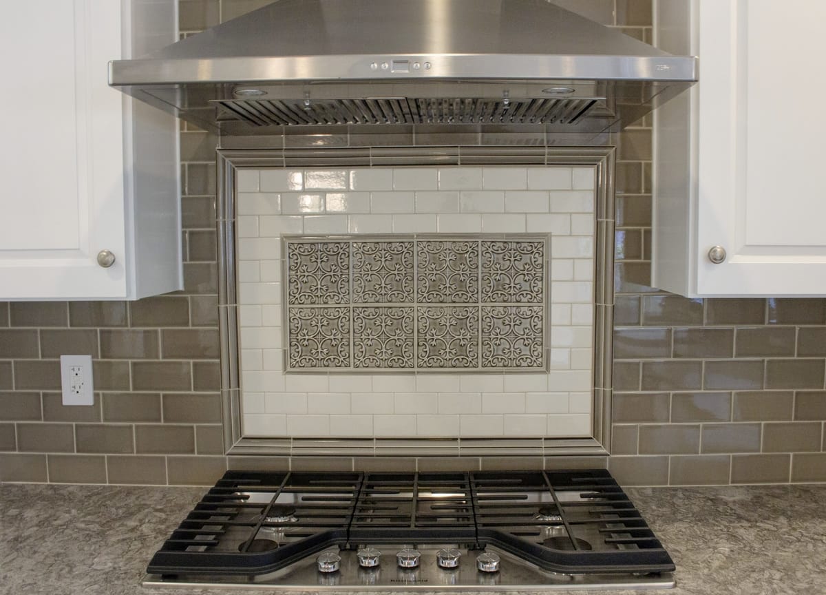 A range top with gas burners and an ornate backsplash, part of a complete home remodel in Burbank, California by design-build firm A-List Builders.