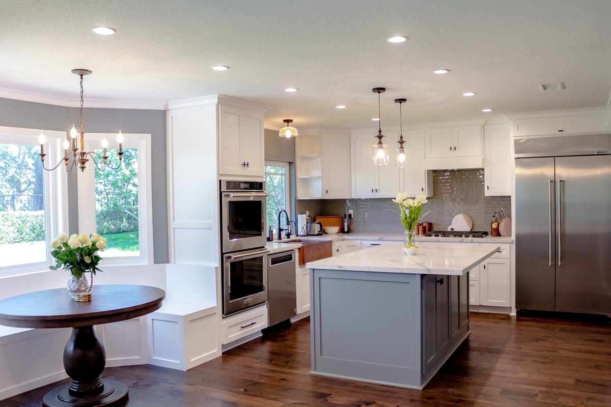 A kitchen and breakfast nook featuring white cabinetry and wooden floors, part of a complete home remodel in Porter Ranch, California by A-List Builders.