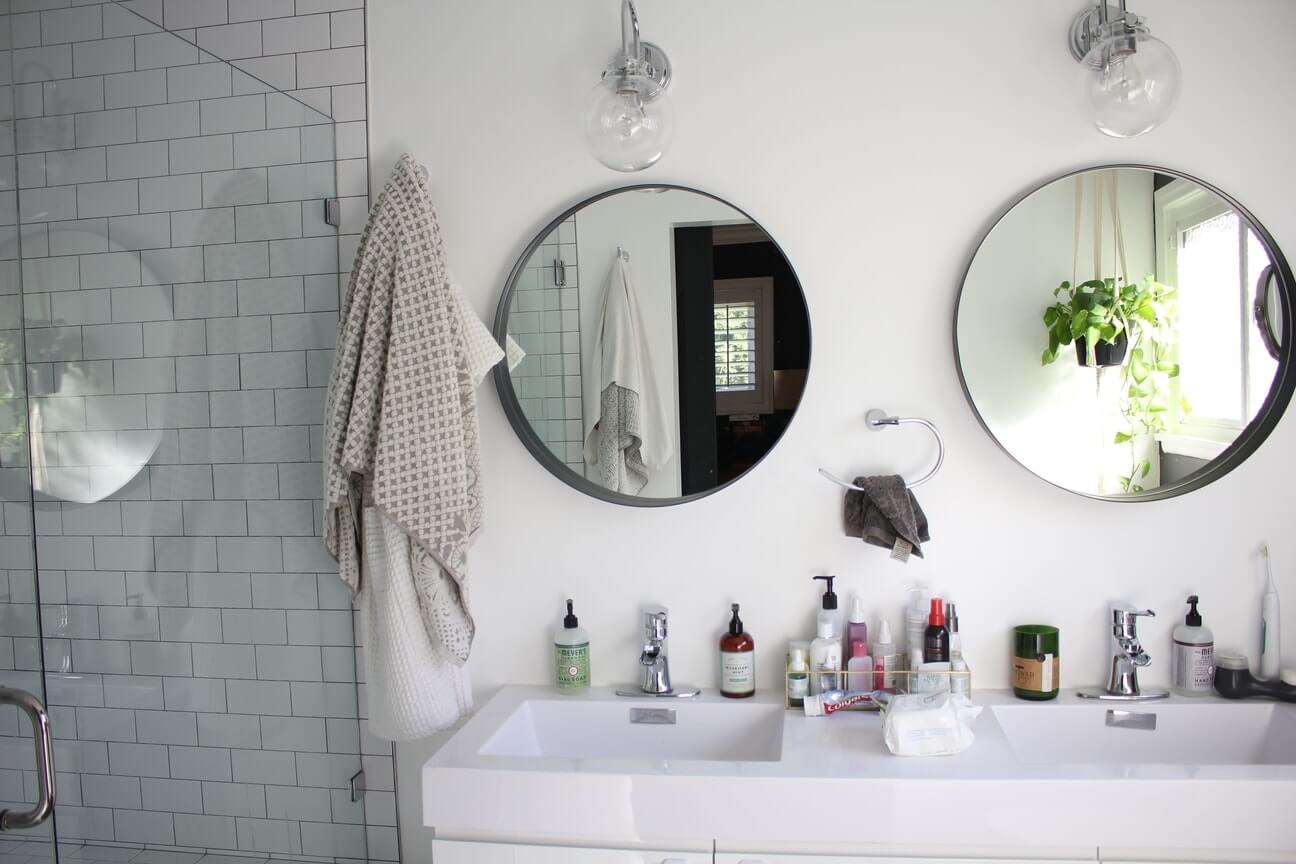 A double sink bathroom vanity with separate hanging round mirrors, part of a home remodel by design-build firm A-List Builders, serving all of Los Angeles.