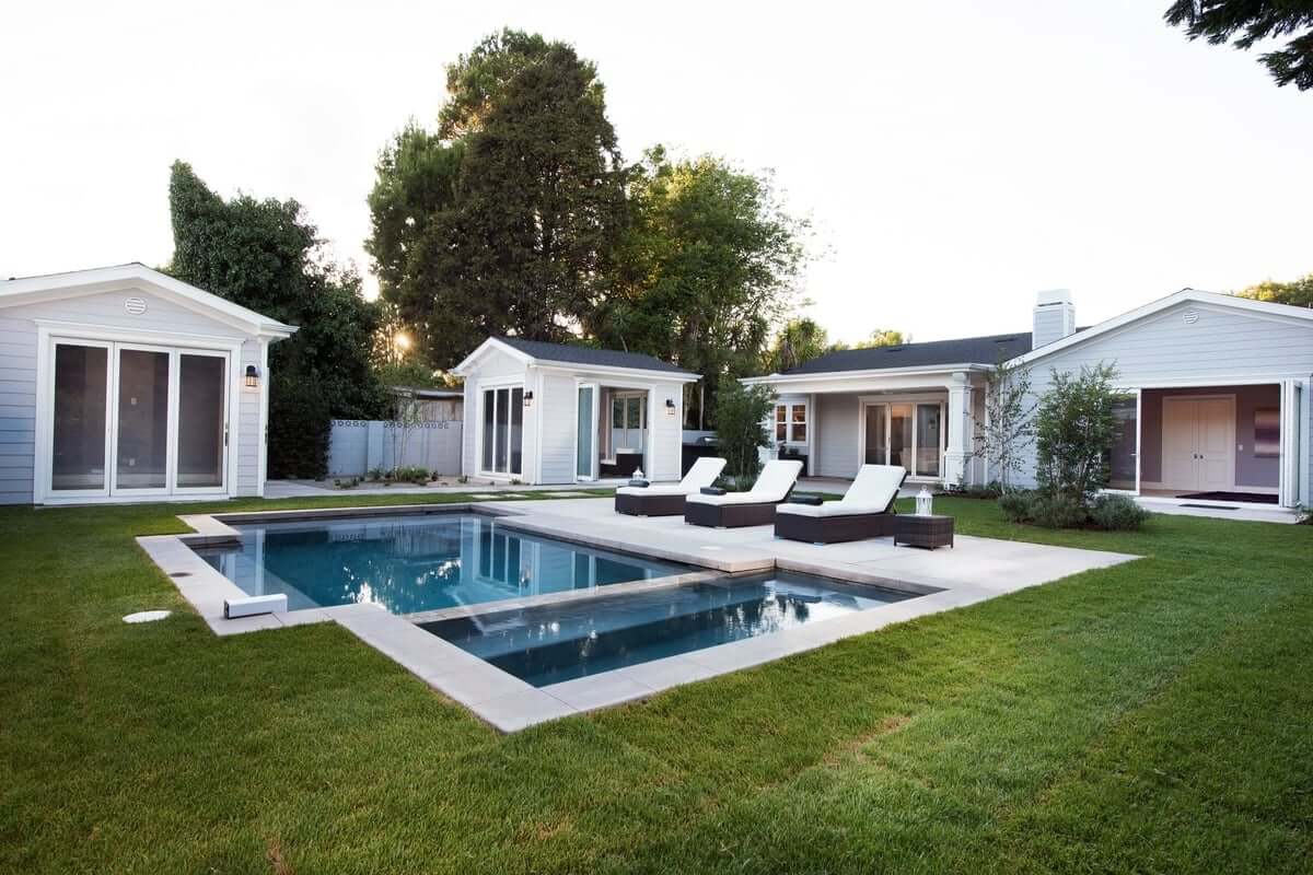 A swimming pool in the middle of a backyard lawn, part of a home remodel by Los Angeles design-build firm A-List Builders.