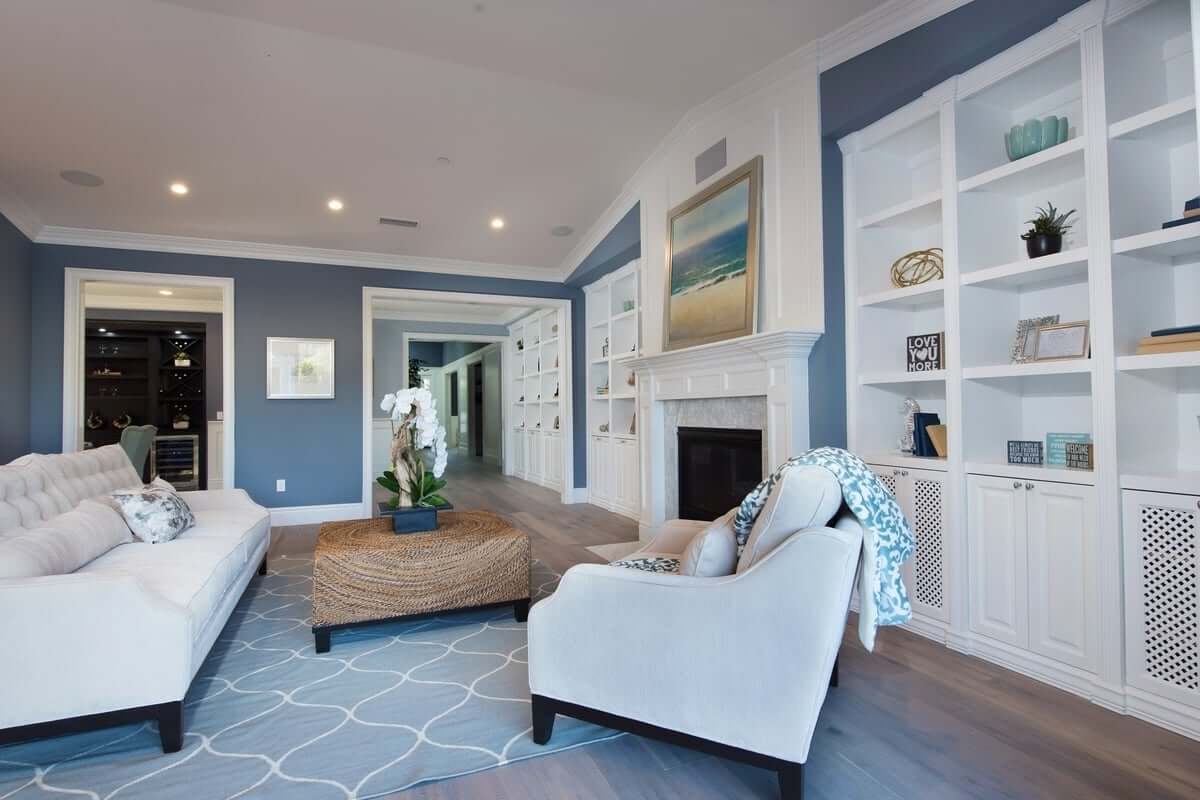 A luxurious living room with hardwood floors and a gray, blue, and white color scheme, part of a home remodel by Los Angeles design-build firm A-List Builders.