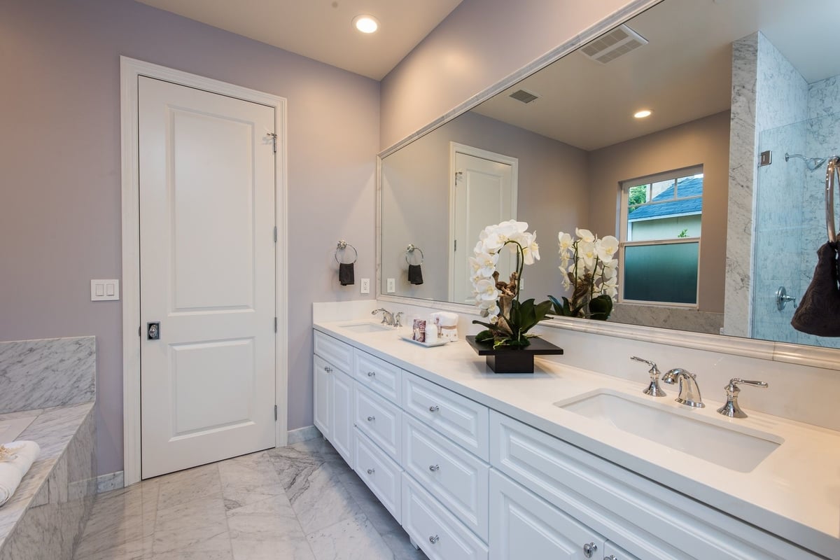 This luxurious bathroom features polished stone on most of its surfaces, part of a home remodel by Los Angeles design-build firm A-List Builders.