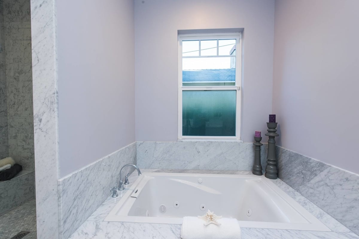 A jacuzzi tub done in polished white and gray stone, part of a complete home remodel by Los Angeles design-build firm A-List Builders.