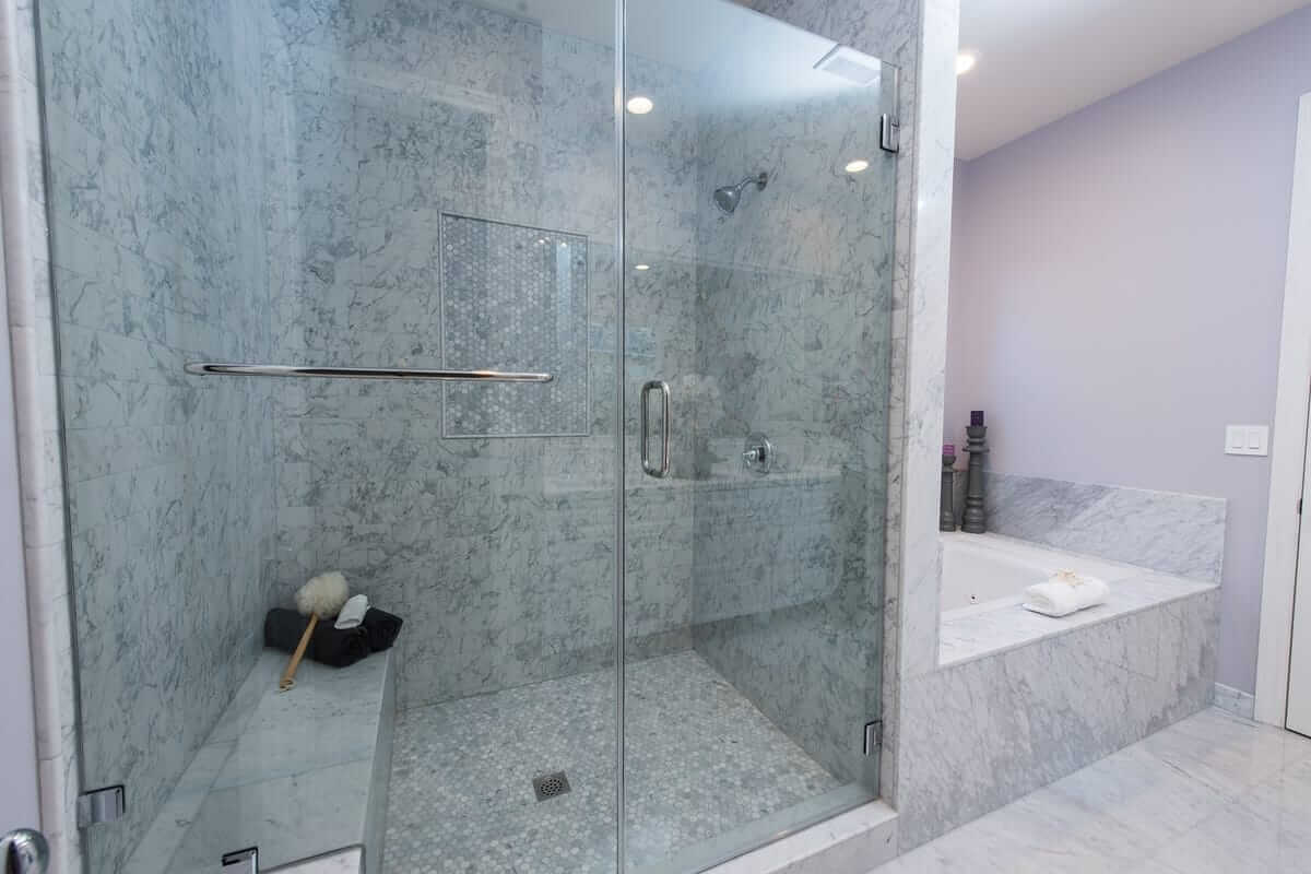 A large walk in shower done in gray and white tile and stonework, part of a home remodel by Los Angeles design-build firm A-List Builders.