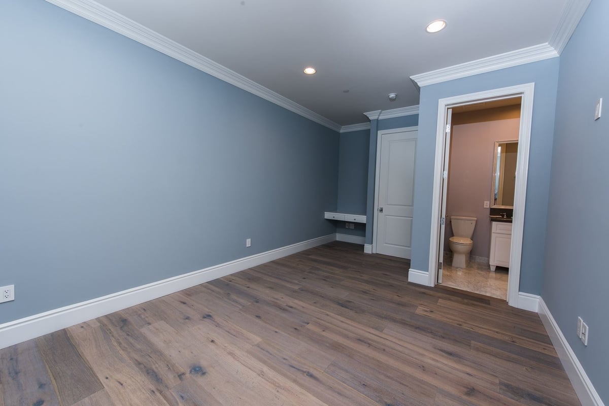 An en suite bedroom with built in study nook, featuring blue walls and hardwood floors, part of a home remodel by Los Angeles design-build firm A-List Builders.