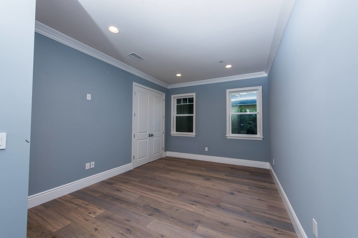 A spare room with hardwood floors, blue gray walls, and white accents, part of a home remodel by Los Angeles design-build firm A-List Builders.