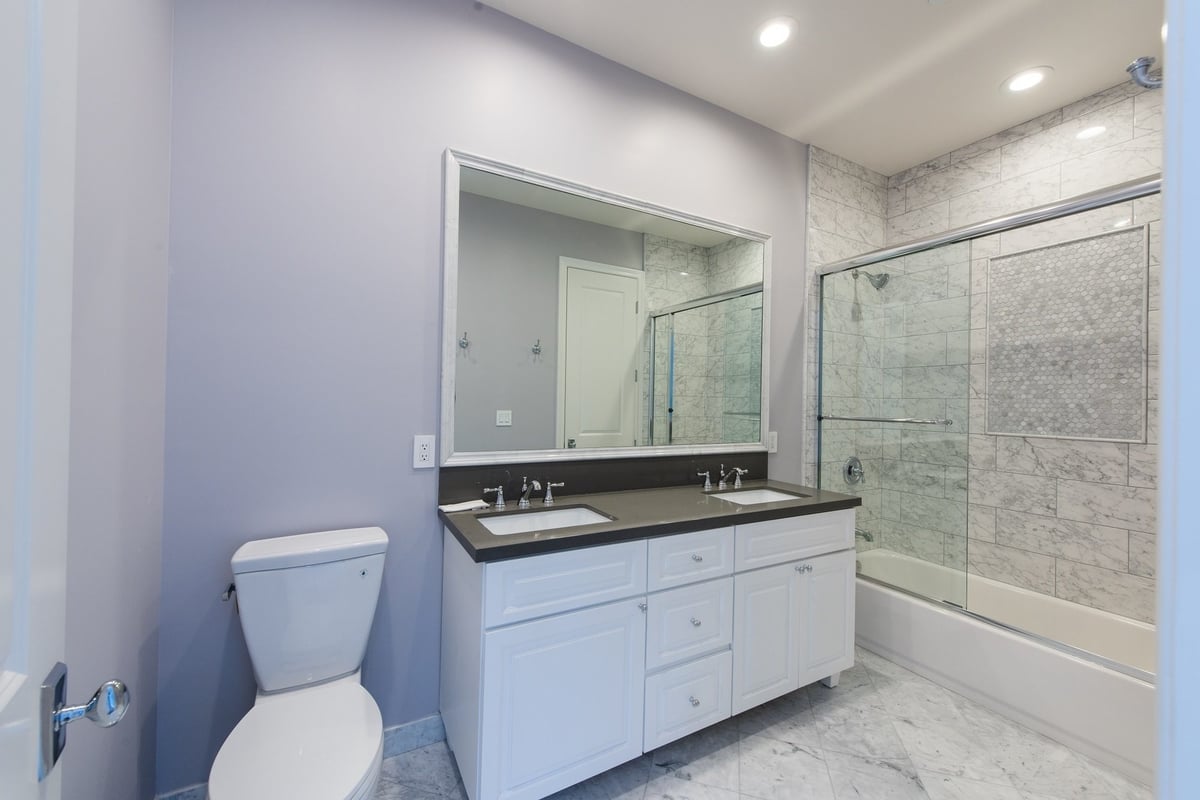 A double sink bathroom vanity and glass door shower, part of a home remodel by Los Angeles design-build firm A-List Builders.