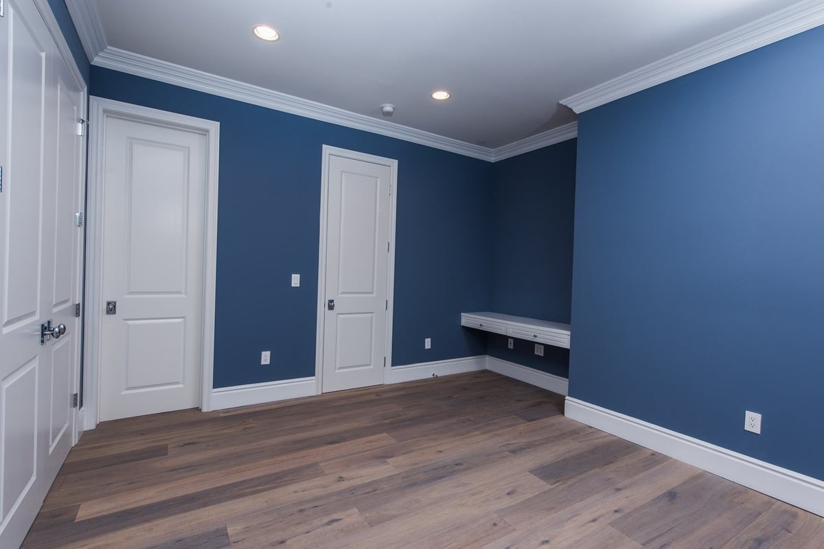 A living room with blue walls, white slanted ceilings, and rich hardwood floors, part of a home remodel by Los Angeles design-build firm A-List Builders.