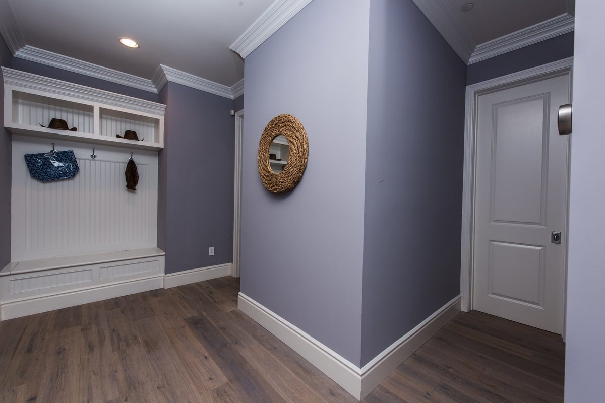 Blue-gray walls, hardwood floors, and white seating accommodate this spacious foyer, part of a home remodel by Los Angeles design-build firm A-List Builders.