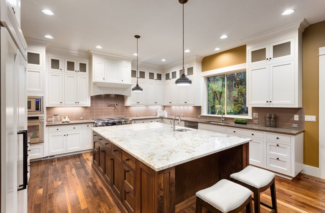 Wooden floors and island cabinets complement a white color scheme on the kitchen perimeter, part of a kitchen remodel in Los Angeles, CA by A-List Builders.