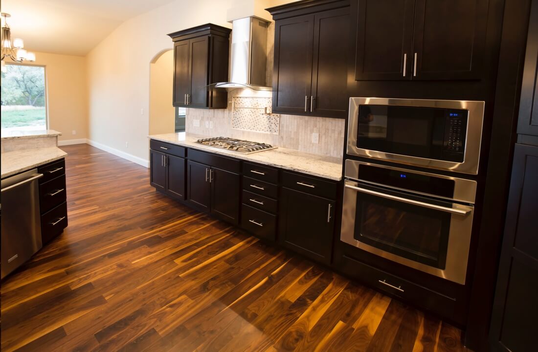 A wall oven, range top, and dark wooden cabinetry, part of a kitchen remodel in Los Angeles, California by design-build firm A-List Builders.